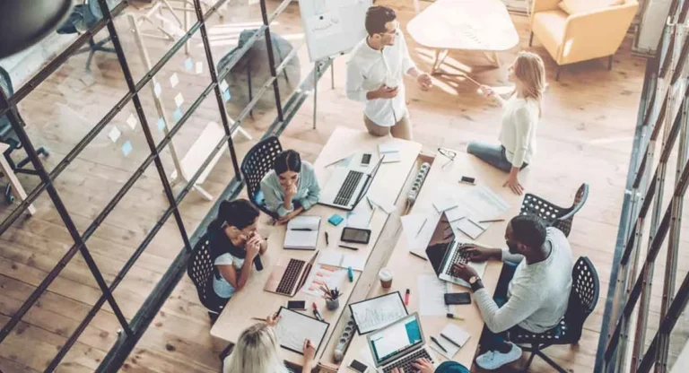 office working persons around a big table that have laptop on that